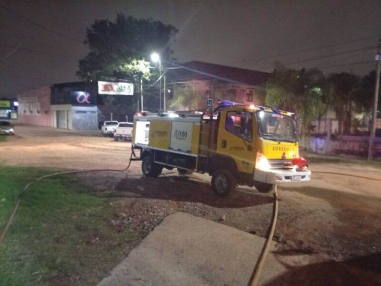 Bomberos trabajando en la extinción de un incendio en un depósito de Corrientes capital, con humo visible.