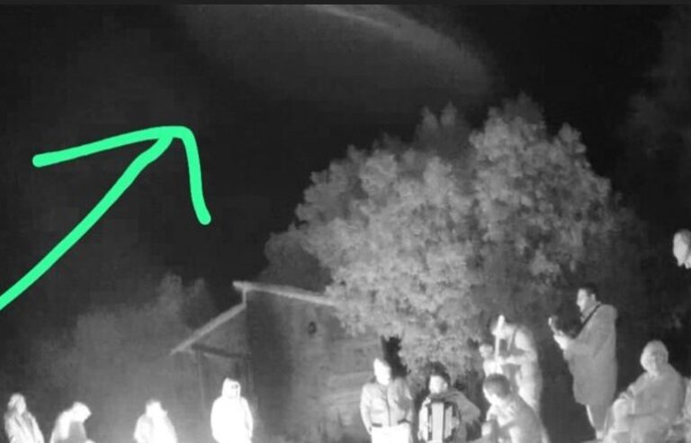 Fotografía en blanco y negro que muestra un objeto cilíndrico sobre un grupo de personas alrededor de un fogón