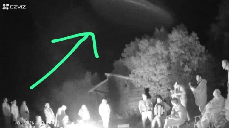 Fotografía en blanco y negro de un objeto cilíndrico sobre un grupo de personas durante un fogón en Caá Catí